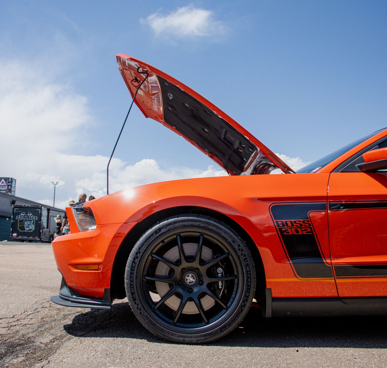 Side profile of a Ford Mustang Boss 302 with its hood open under a clear blue sky.