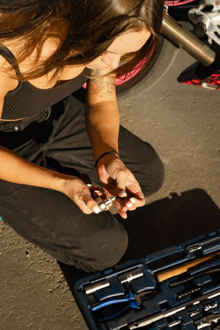Young woman examines tools from a kit on a sunny day, focusing on a project.